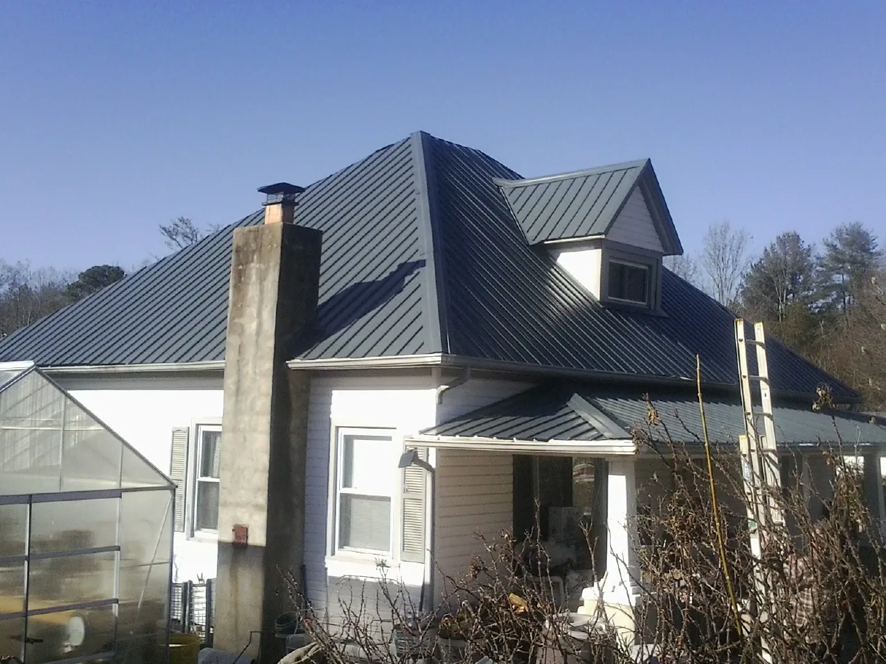 Dark blue standing seam metal roof on a white farmhouse with dormer — Slate & Tile Roof Repair by Roofing Brothers in Millington